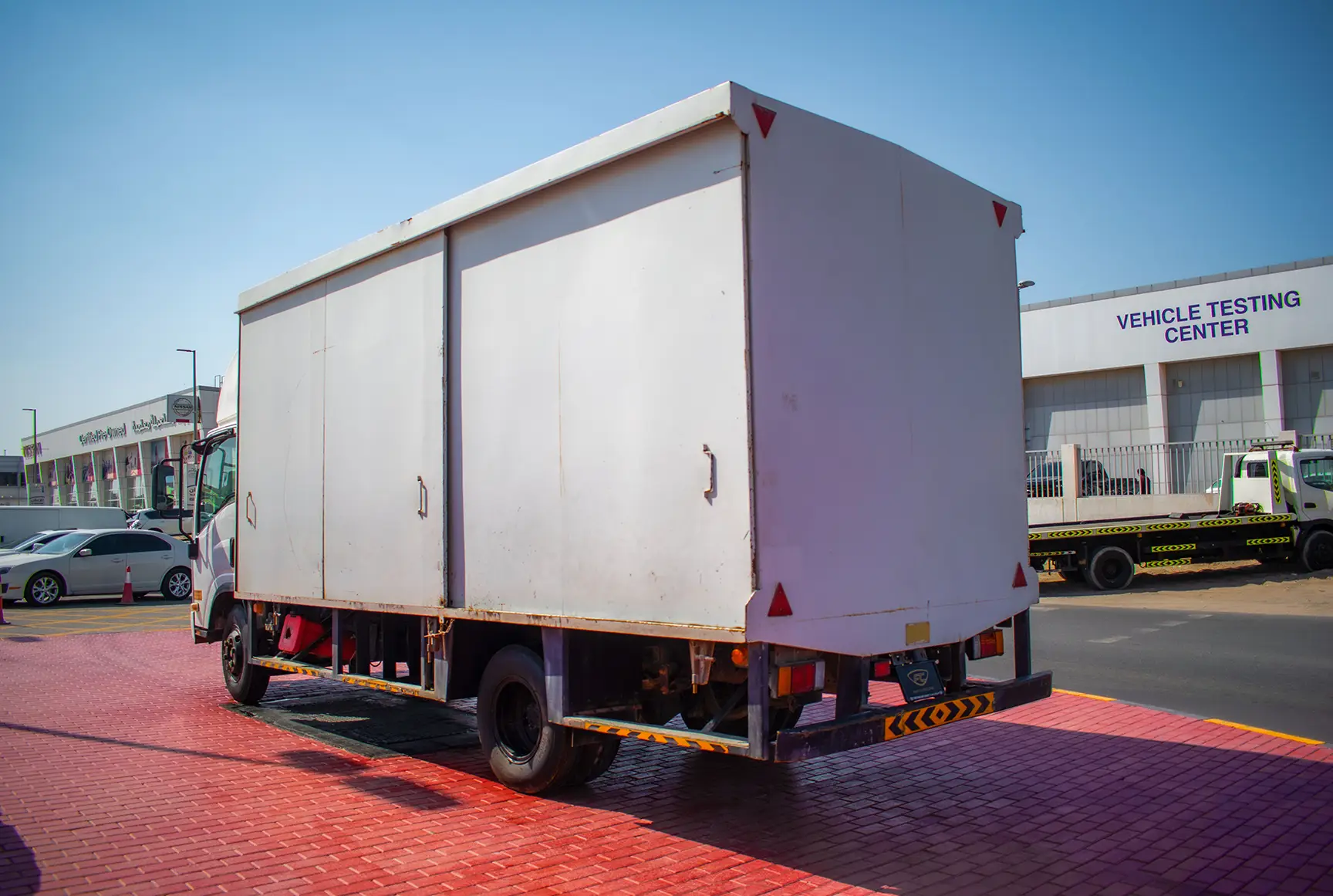 Used 2019 Isuzu NPR Cargo Box in White – Left Back Diagonal (45°) View for Sale at First Choice Cars Dubai Sharjah
