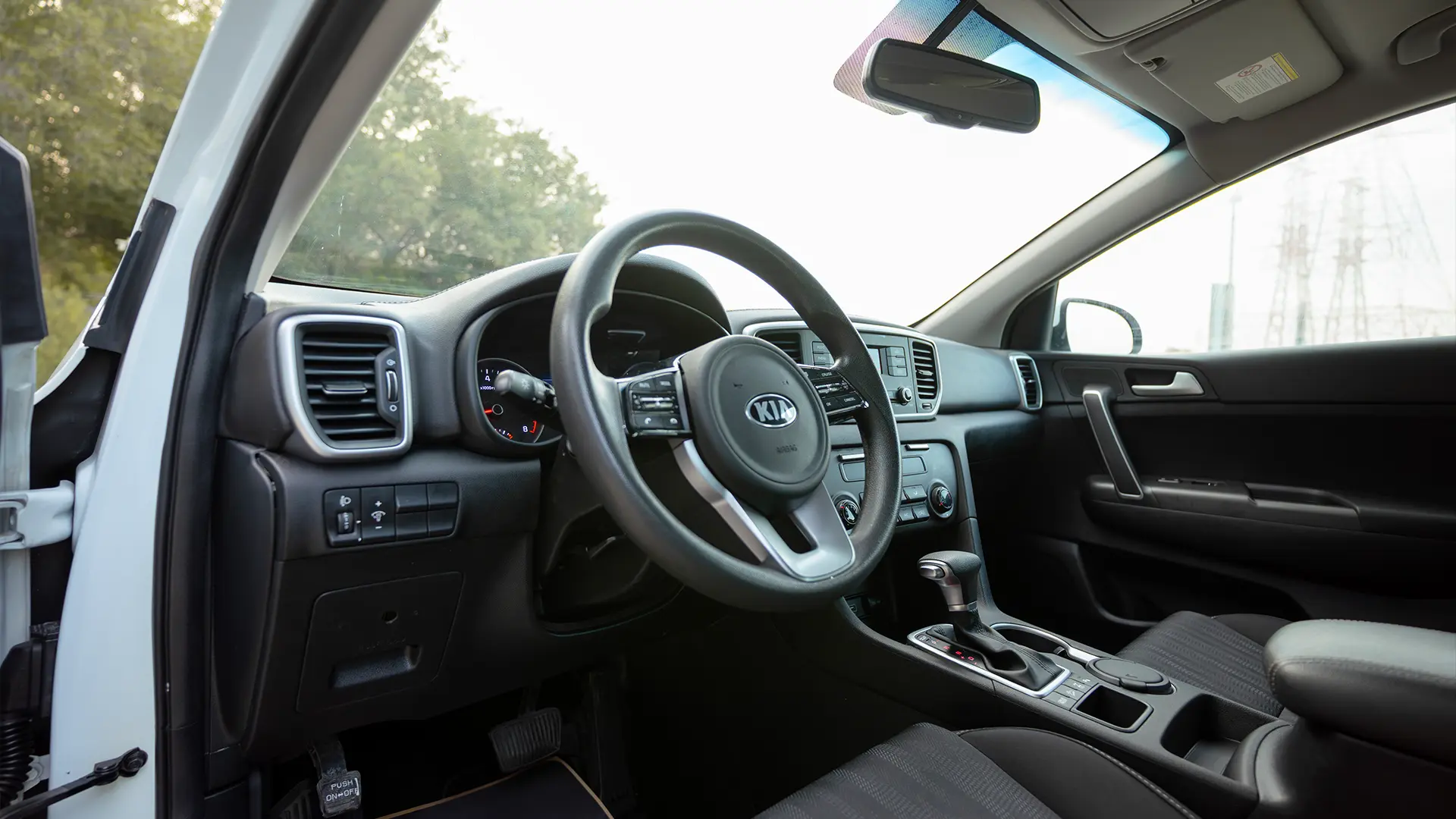 Used 2020 Kia Sportage LX in White – Driver Side Dashboard & Steering View for Sale at First Choice Cars Dubai Sharjah